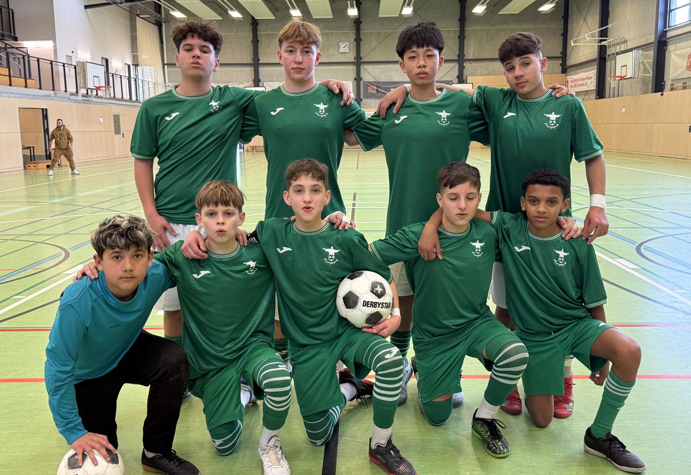 Tým mladých hráčů v zelených dresech ve sportovní hale