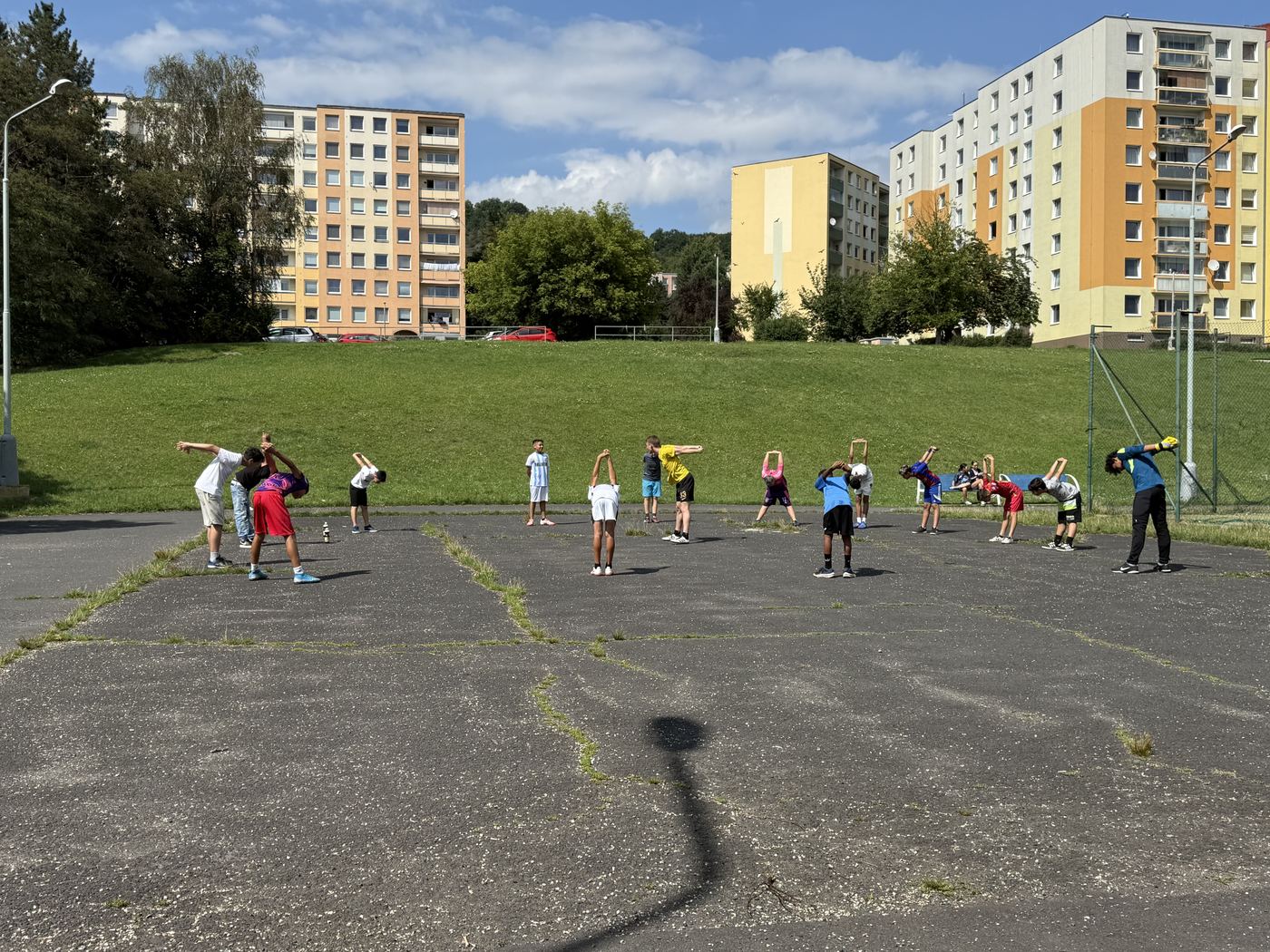 Rozcvička dětí na asfaltové ploše před paneláky