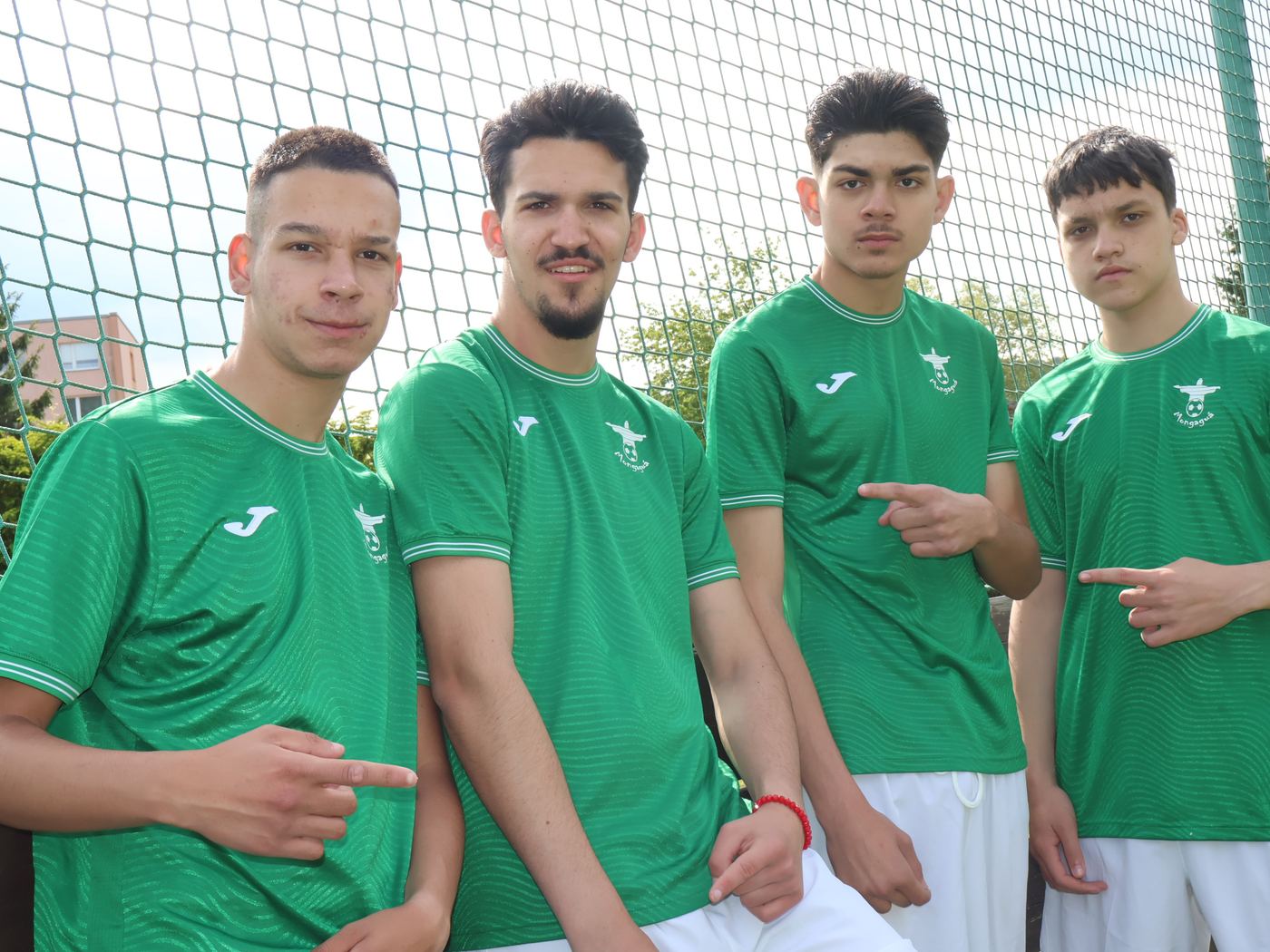 Starší hráči v zelených dresech Mongaguá pózují u oplocení hřiště